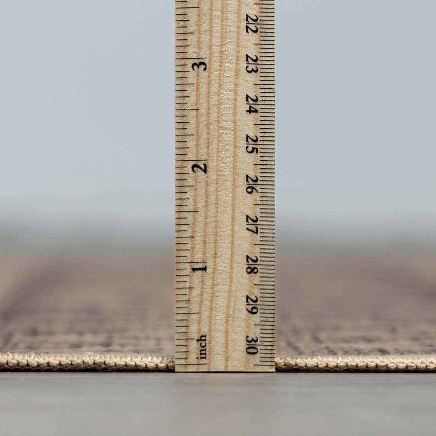 Close-up of Halle Beige Washable Area Rug thickness, showing beige and dark brown tones with a ruler for scale. Pile