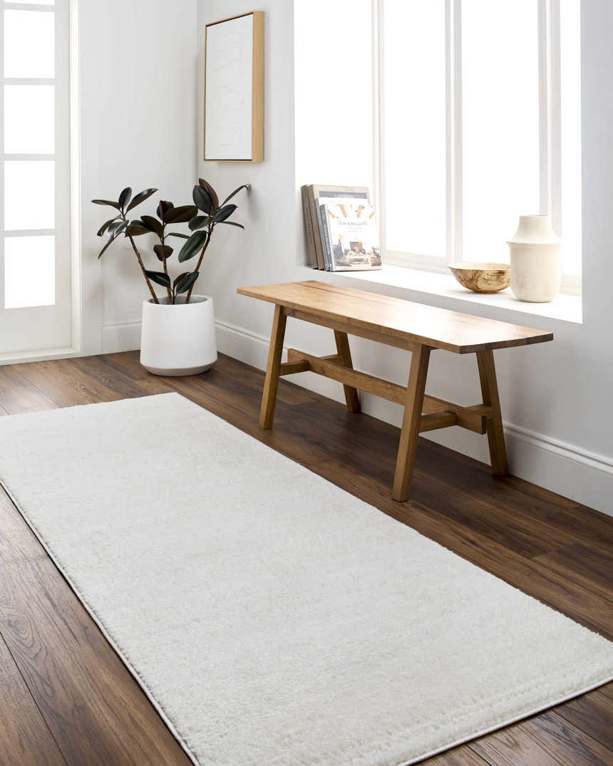 Entryway with Julie Ivory Area Rug runner, wood bench, dark wood floors, and white walls. Roomscene-Runner