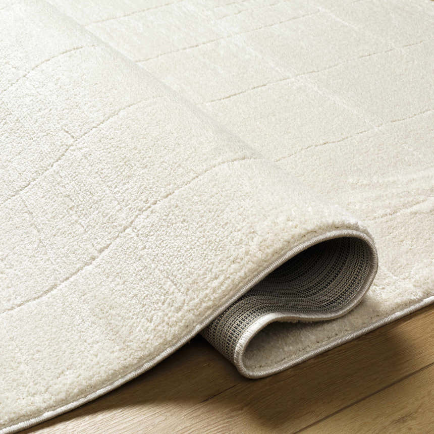 Close-up of the ivory Keanu Area Rug showing its subtle grid pattern and soft, plush texture on a wood floor. Fold