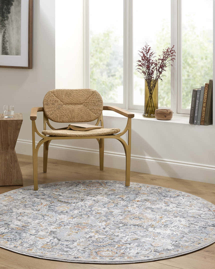 Sunlit room with a round Atara Area Rug in gray, brown, and nutmeg under a woven chair. Roomscene-Round
