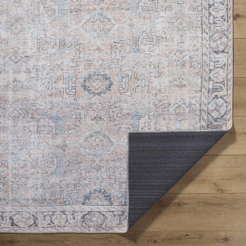 Close-up of the Giona Washable Area Rug showing its vintage Persian design and colors: blue, charcoal, light blue, and pastel red. Fold