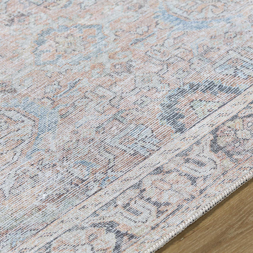 Close-up of the Giona Washable Area Rug showing a vintage Persian pattern in blue, charcoal, red, and green on a light background. Texture