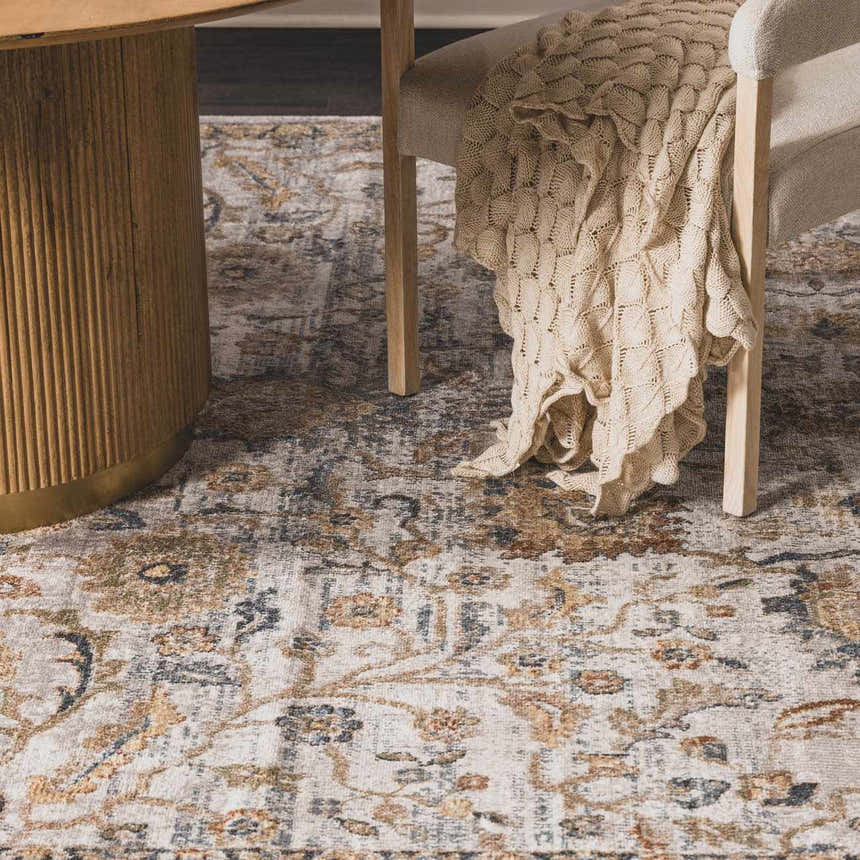 Close-up of the Dion Washable Floral Rug showing its charcoal, beige, and gray floral pattern under a table and chair. Styleshot