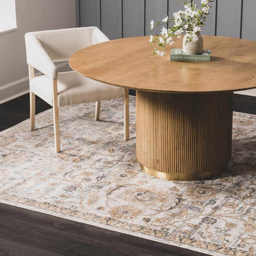Dining room scene with a round wood table on a Dion Washable Floral Rug in charcoal, beige, and gray. Neutral chair and dark wood floors. Roomscene-Rectangle