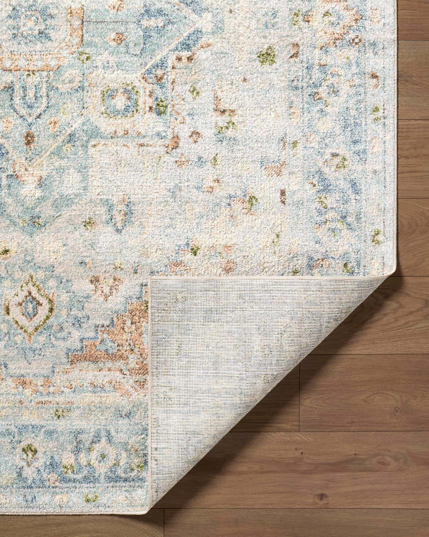 Close-up of the Ezri Washable Area Rug showing its beige, light blue, and orange farmhouse traditional pattern and machine woven texture. Fold
