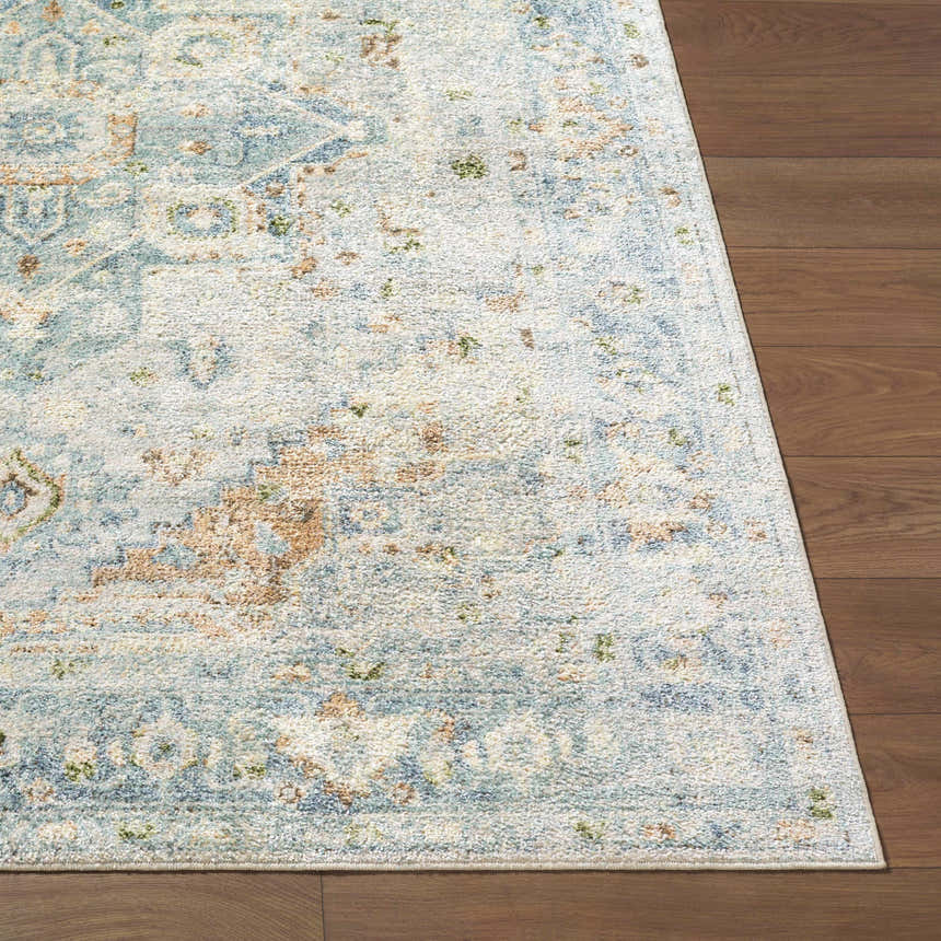 Close-up of Ezri Washable Area Rug showing beige, light blue, and orange traditional farmhouse pattern on wood floor. Front