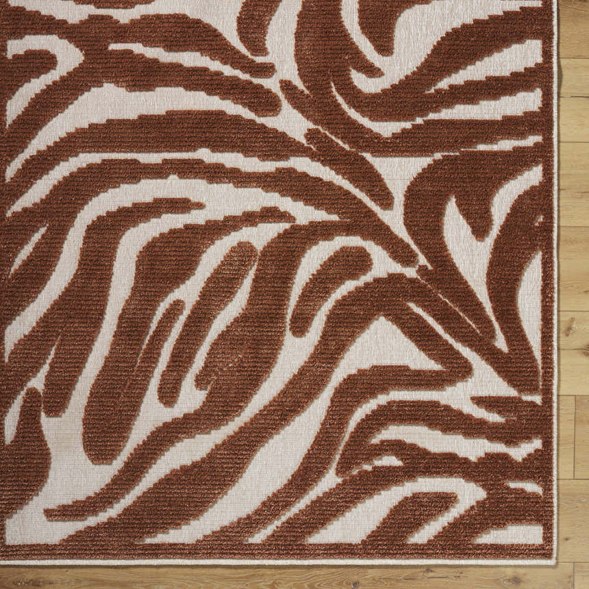 Close-up of the Keto Brown Washable Area Rug. Features a contemporary brown and off-white abstract pattern. Corner