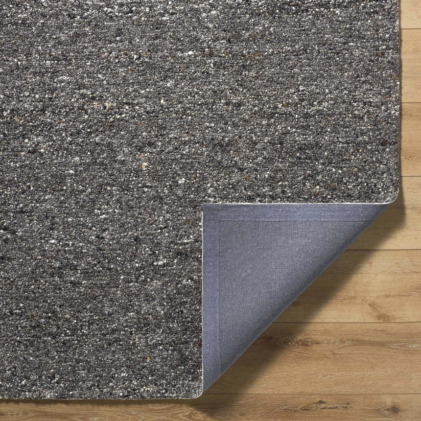 Close-up of the hand-tufted Sevan Black Wool Area Rug showing its jet black, medium gray, and taupe textured design. Fold