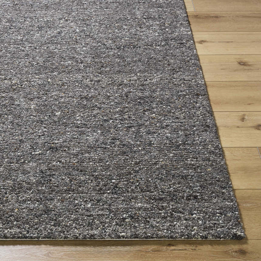 Close-up of the hand-tufted Sevan Black Wool Area Rug showing its textured weave and blend of jet black, gray, and taupe tones. Front
