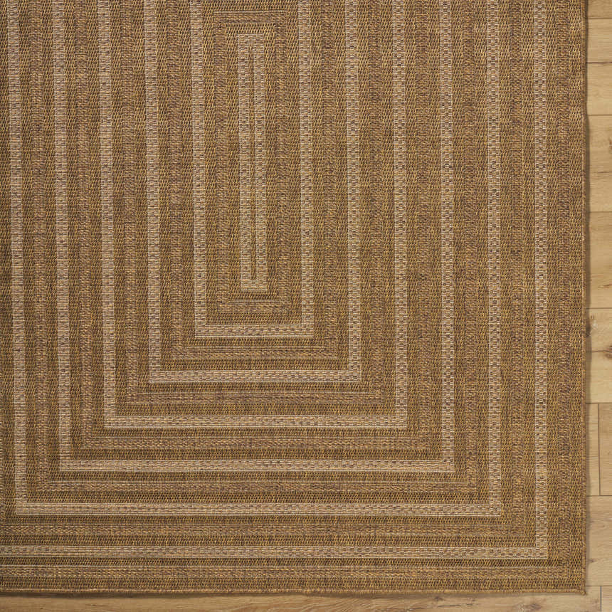 Close-up of the Dyami Flatweave Faux Jute Rug. Features a geometric pattern and woven texture in camel and light brown tones. Corner