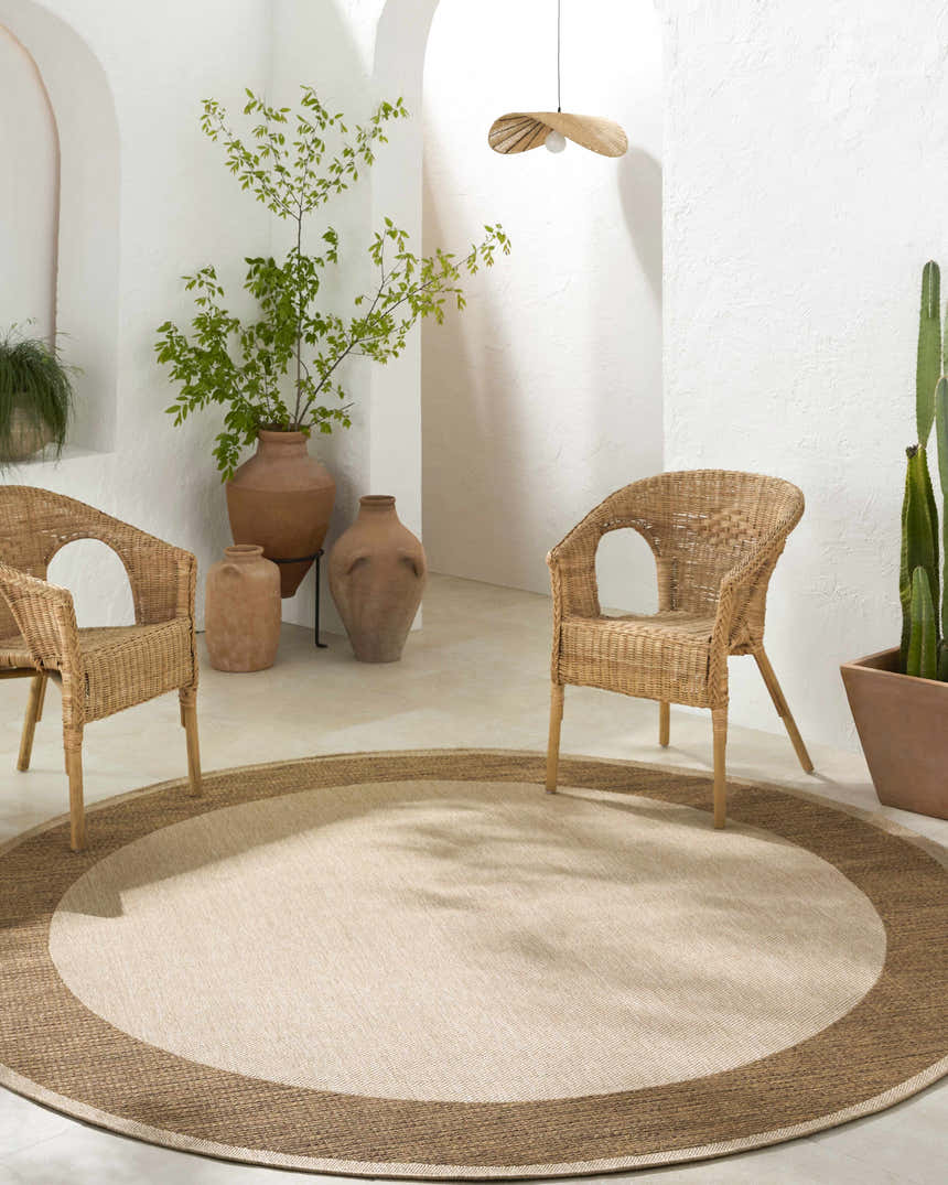 Neutral room scene with Inigo Flatweave Faux Jute Rug, wicker chairs, terracotta pots, and white textured walls. Roomscene-Round
