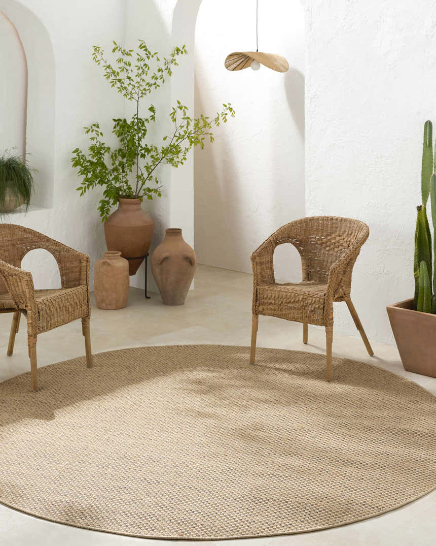 Neutral patio scene with wicker chairs and a round Zeta Flatweave Faux Jute Rug in beige and brown tones. Roomscene-Round