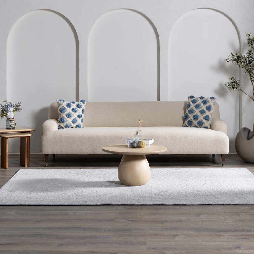 Living room scene with a light gray Isako Blue & Gray Solid Washable Area Rug, beige sofa, and round coffee table. Roomscene-Rectangle