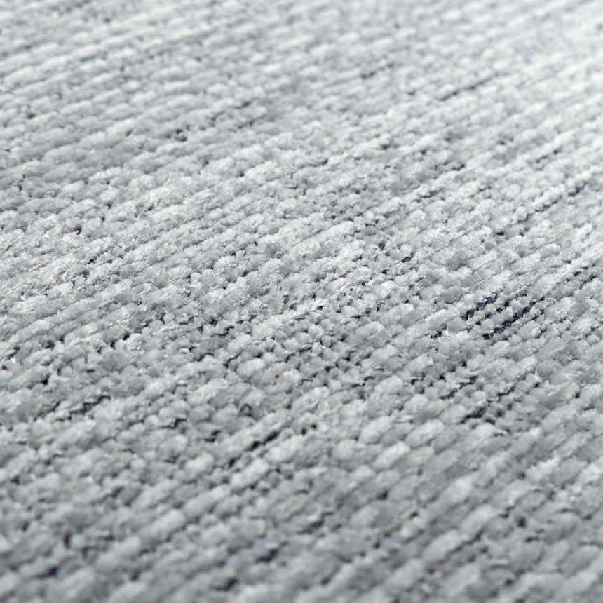 Close-up of the plush texture of the Isako Blue & Gray Solid Washable Area Rug. Light gray polyester fibers. Texture