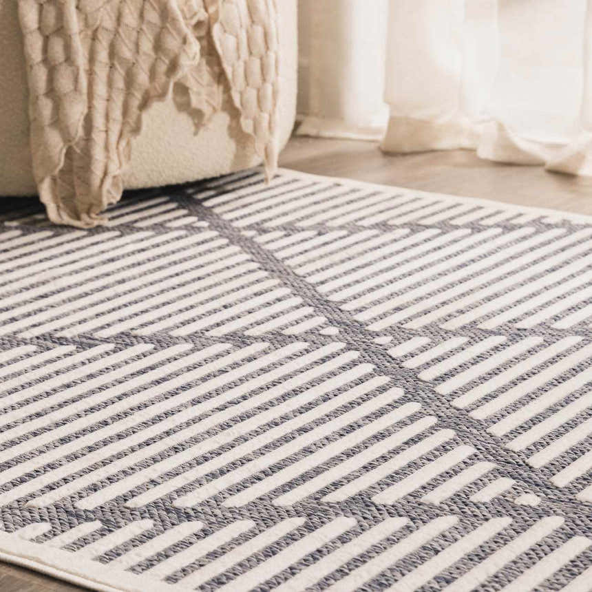Close-up of Anah Blue Outdoor Rug showing a striped geometric pattern in denim and off-white. Roomscene-Rectangle