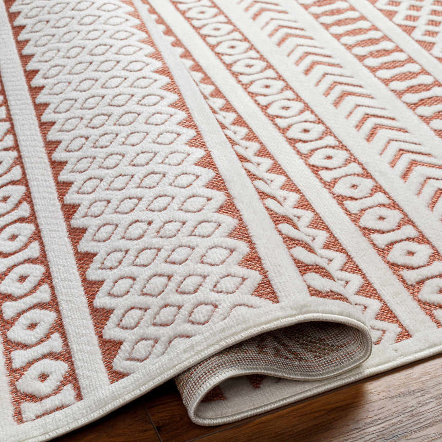 Close-up of the Jove Orange Outdoor Rug showing its bone and terracotta contemporary Southwestern pattern and woven texture. Fold