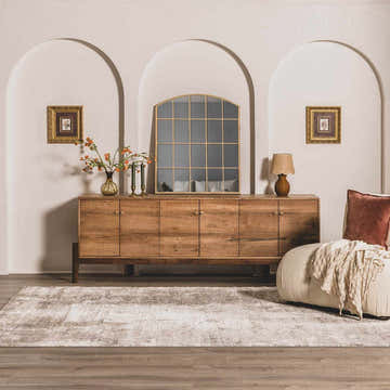 Living room scene with Duval Taupe Abstract Area Rug, wood cabinet, arched wall decor, and cozy ottoman. Roomscene-Rectangle
