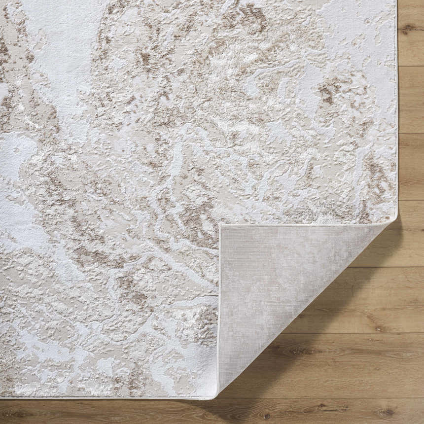 Close-up of the Kaleo Area Rug featuring a beige, cream, and tan contemporary pattern. Folded corner shows the rug's backing. Fold