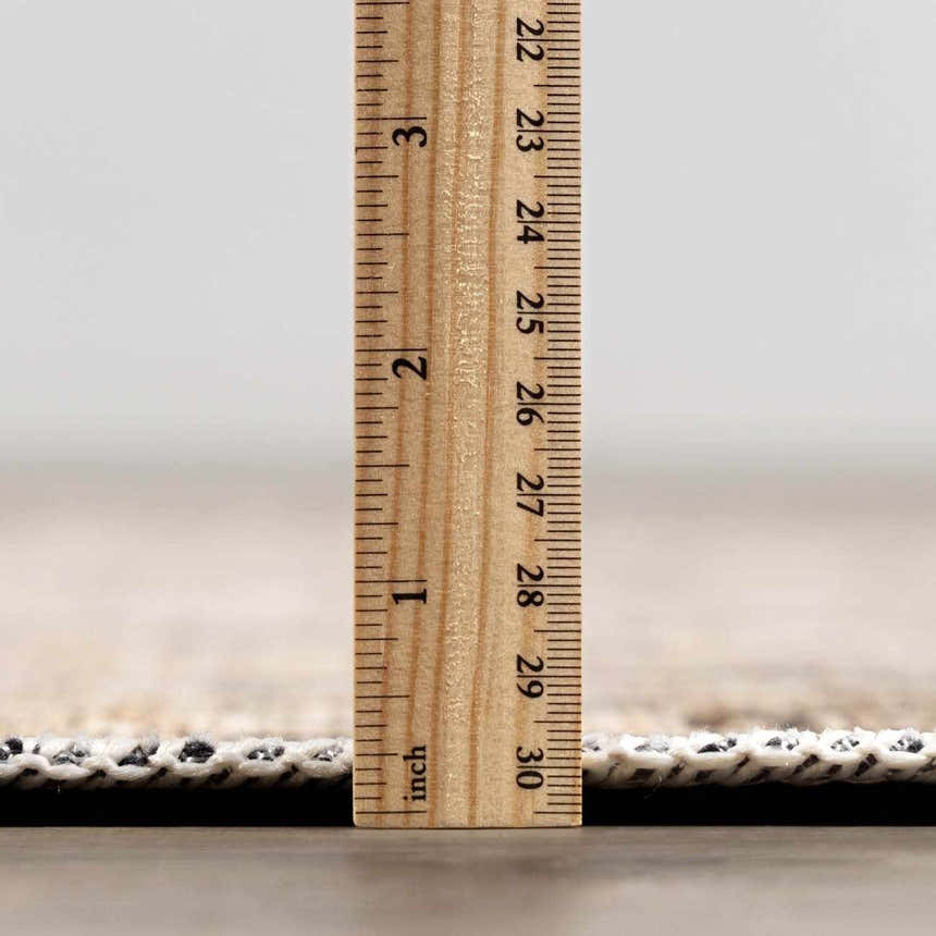 Close-up of the Standon Vintage Flat Pile Washable Rug showing its low pile height with a ruler. Pile