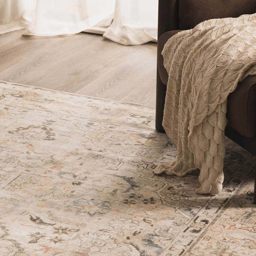 Living room scene with Standon Vintage Flat Pile Washable Rug, brown chair, and knit throw blanket. Neutral tones create a cozy mood. Roomscene-Rectangle