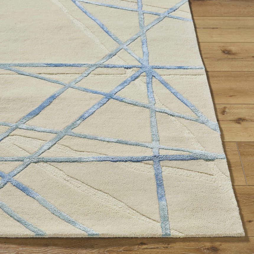Close-up of the Hiba Area Rug. Hand-tufted wool rug in beige with a modern, geometric slate blue pattern. Soft texture. Front