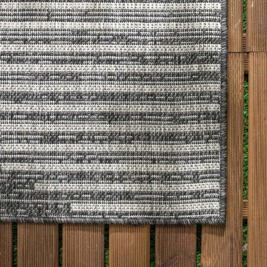 Close-up of the Stephan Area Rug showing a contemporary black, charcoal, and cream striped pattern and woven texture. Swatch