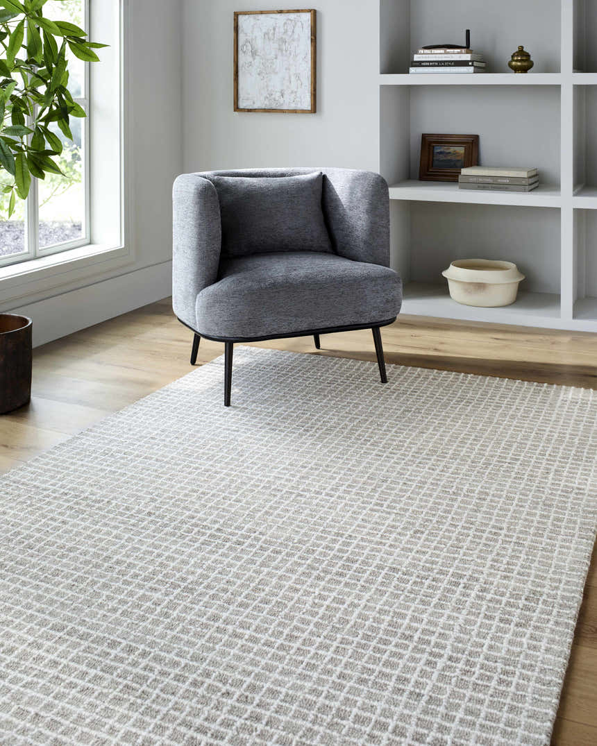 Living room scene with gray chair and Anahid Gray Area Rug, a checkered wool rug in ash and off-white. Roomscene-Rectangle