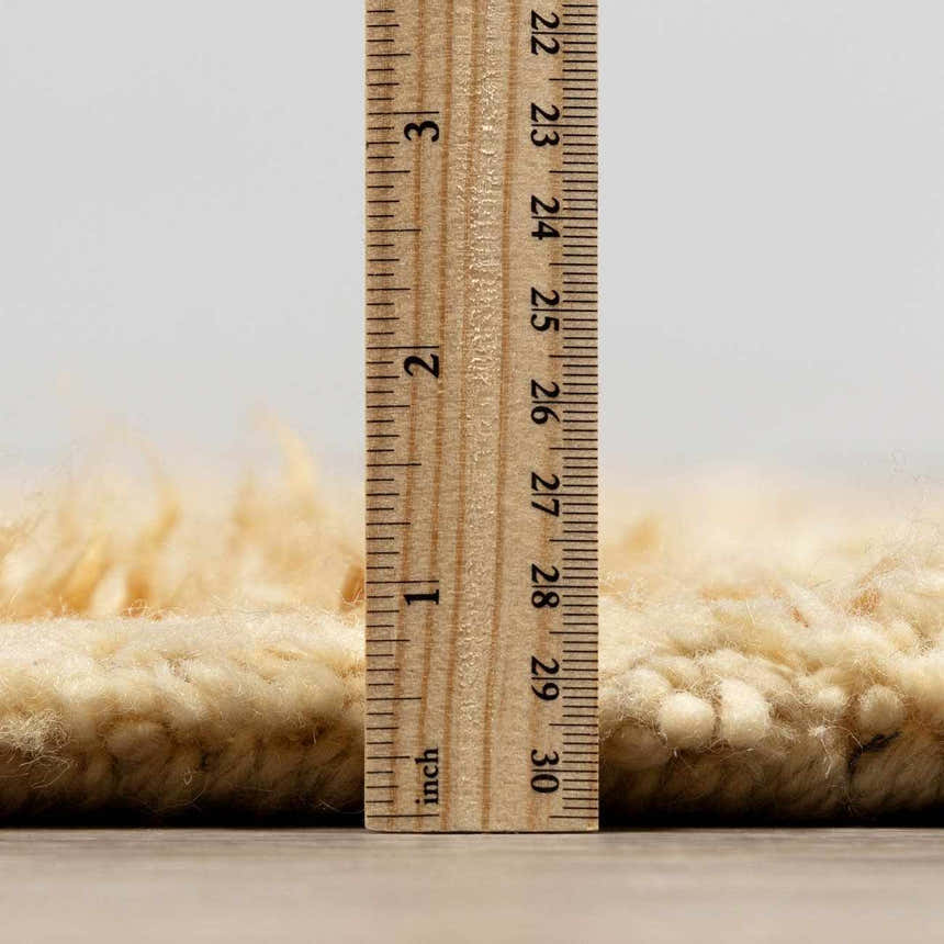 Close-up of the thick, hand-tufted pile of the Pearl Wasim Area Rug, showing its texture and height with a ruler. Pile