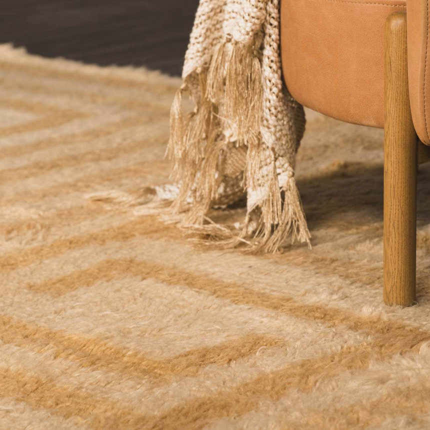 Close up of the tan and camel Wasim Area Rug with geometric pattern and textured wool fibers. Styleshot