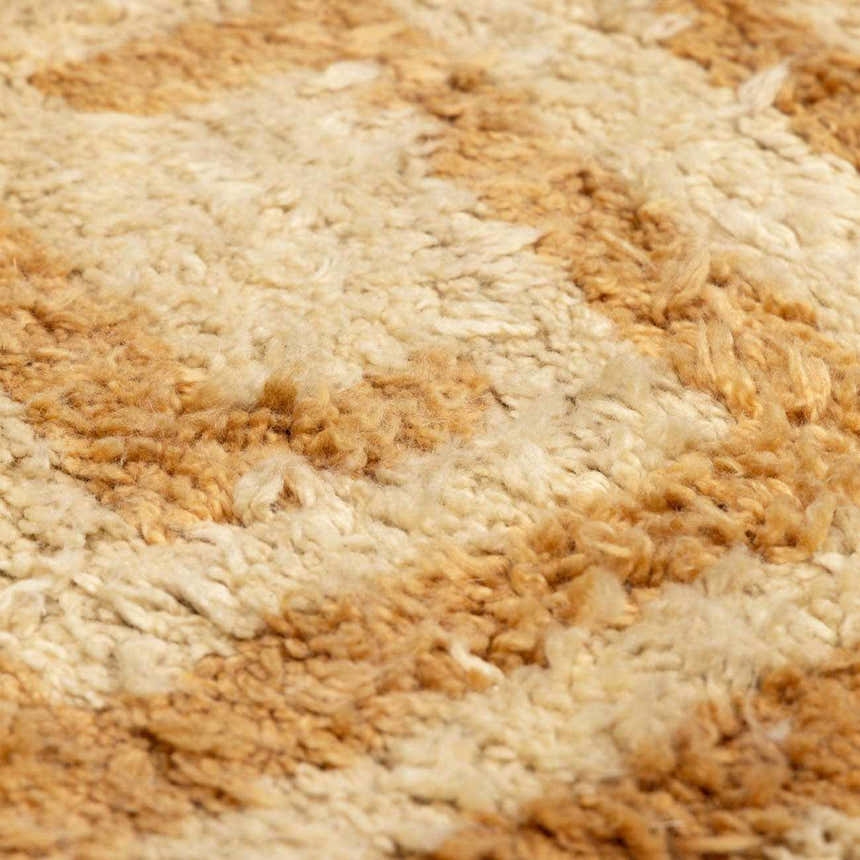 Close up of the hand-tufted Wasim Area Rug, showing its brick red, camel, and tan wool texture. Texture