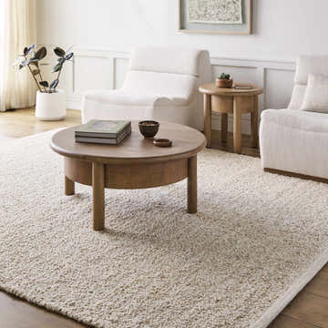 Living room scene with cream chairs, wood table, and the Teela Ivory Area Rug. Roomscene-Rectangle