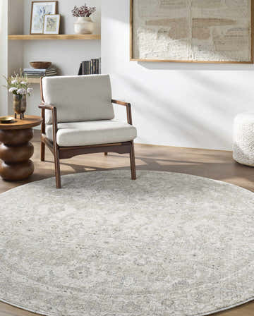 Living room scene with a round cream Tyren Area Rug, light wood floors, and neutral armchair. Roomscene-Round