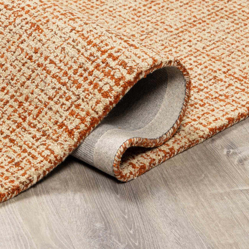 Close-up of the Teresita Area Rug, a hand-tufted wool rug in burnt orange and ivory with a textured, contemporary design. Fold