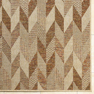 Close-up of the Andrea Burnt Sienna Area Rug. Geometric pattern in beige, rust, sandstone, and terracotta tones. Machine woven texture. Corner