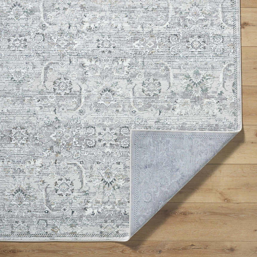 Close up of the Tariq Area Rug, a traditional rug in silver gray and slate blue, with a floral pattern. Fold