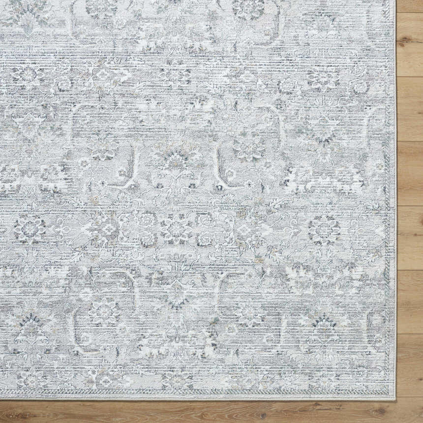Close-up of the Tariq Area Rug. Silver gray, slate blue, and sterling gray traditional floral pattern. Machine woven. Corner