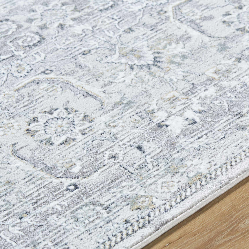 Close-up of the Tariq Area Rug. Machine-woven rug in silver gray, slate blue, and sterling gray with a traditional pattern. Texture
