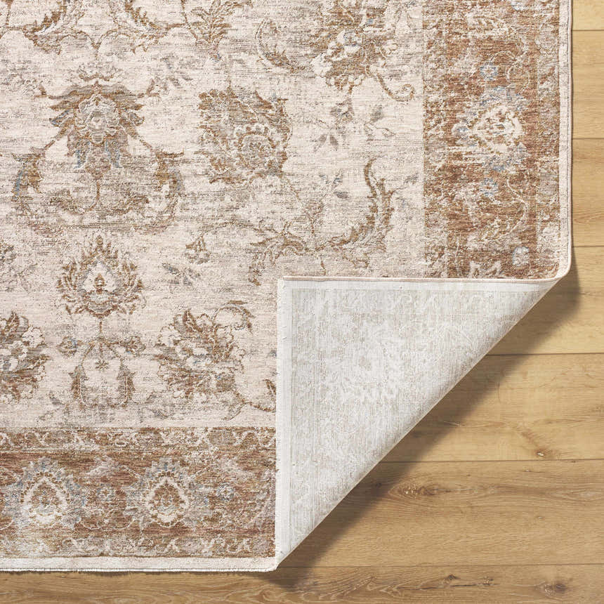Close-up of the Tylie Blue Area Rug showing its cream, tan, and blue traditional floral pattern and machine-woven texture. Fold