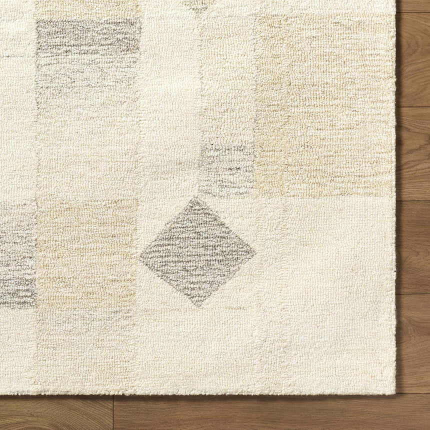 Close up of the hand-tufted Tovah Area Rug. Ash, light silver, and cream wool with geometric shapes. Contemporary style. Corner