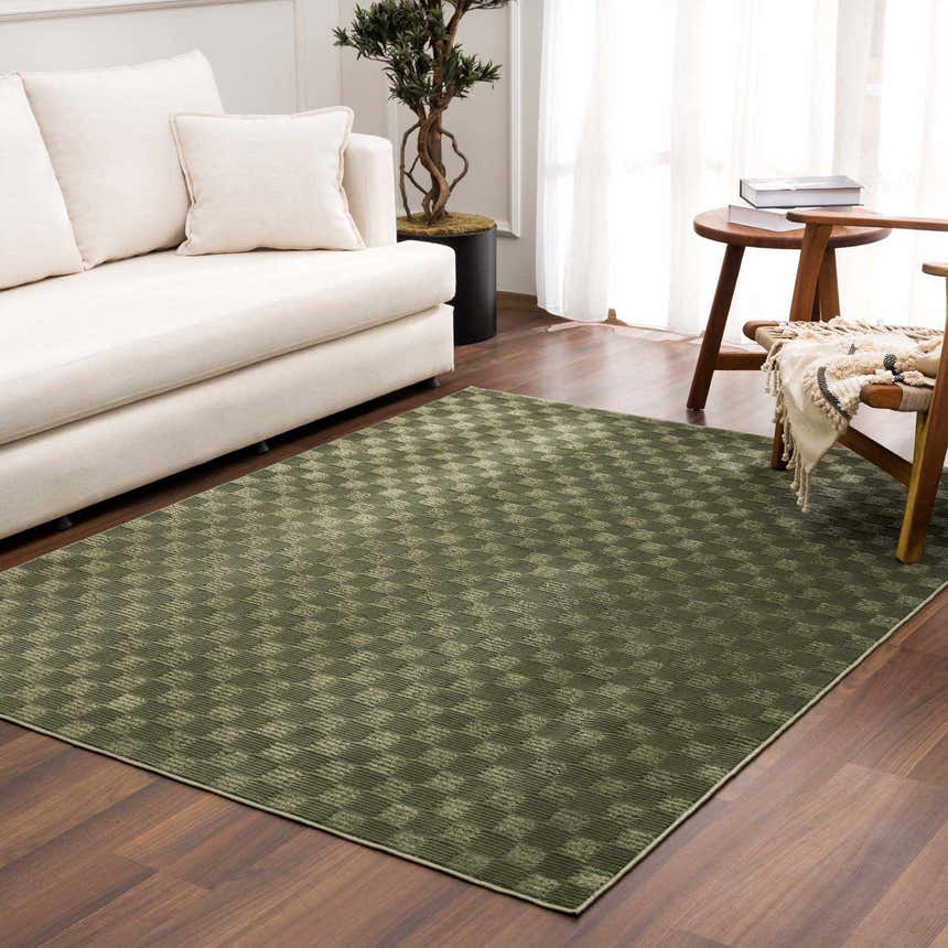 Living room scene with a Truls 3D Checkered Washable Rug - Green, cream sofa, wood chair, and dark wood floors. Roomscene-Rectangle