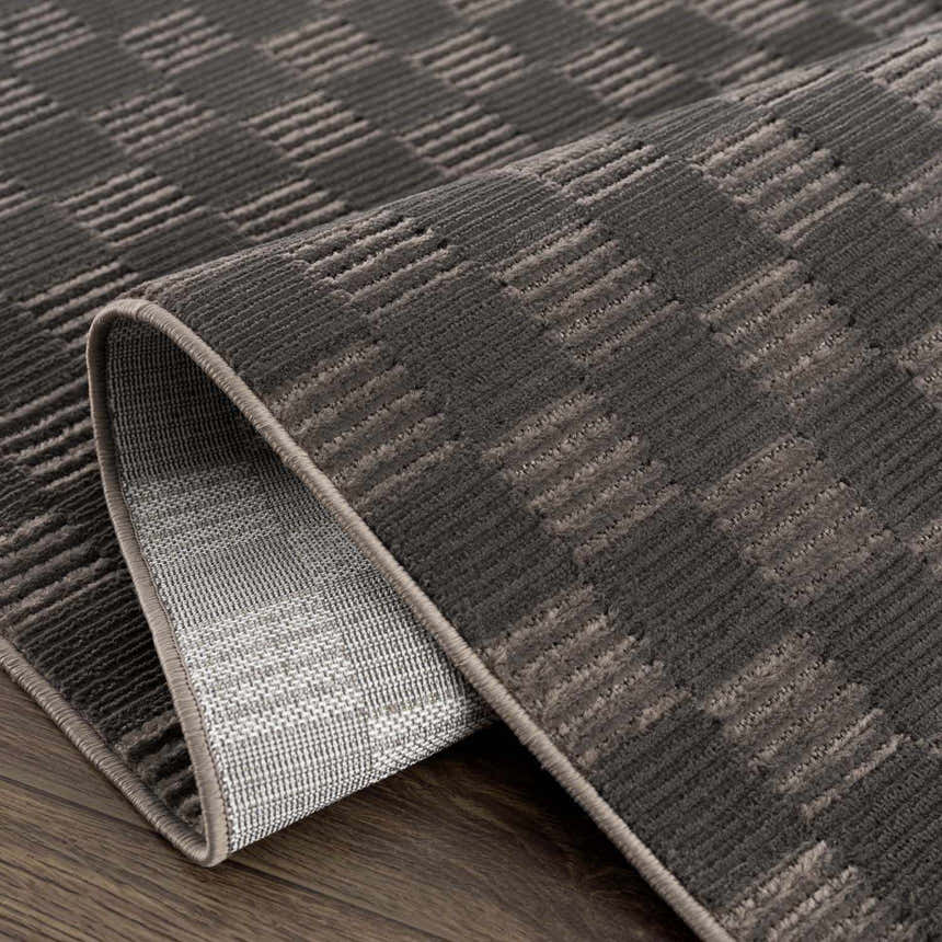 Close-up of the black Truls 3D Checkered Washable Rug, showing the textured checkered pattern and machine-woven construction. Fold