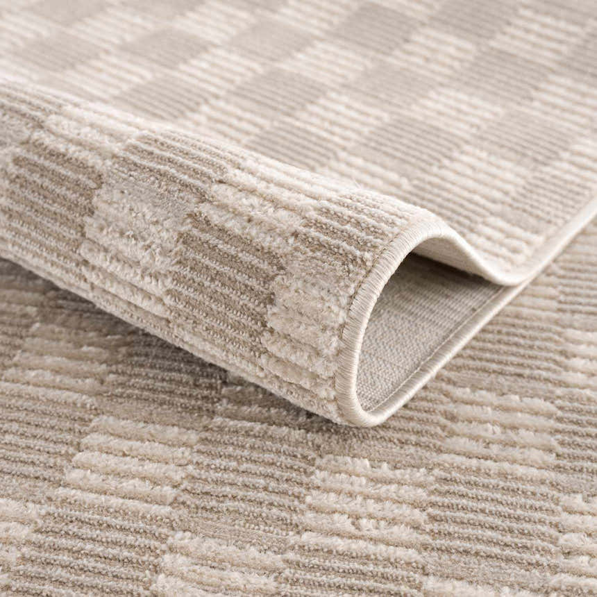 Close-up of the Truls 3D Checkered Washable Rug in Biscotti. Beige and cream checkered pattern with a soft, textured pile. Fold