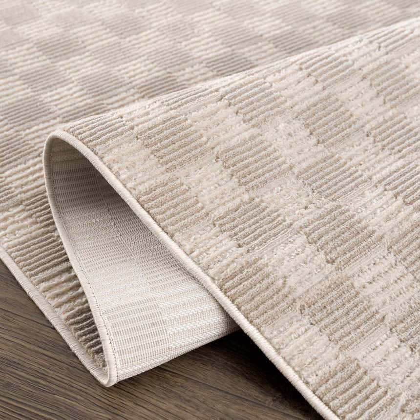 Close-up of the Truls 3D Checkered Washable Rug in Biscotti. Beige and cream checkered pattern with a textured, machine-woven design. Fold