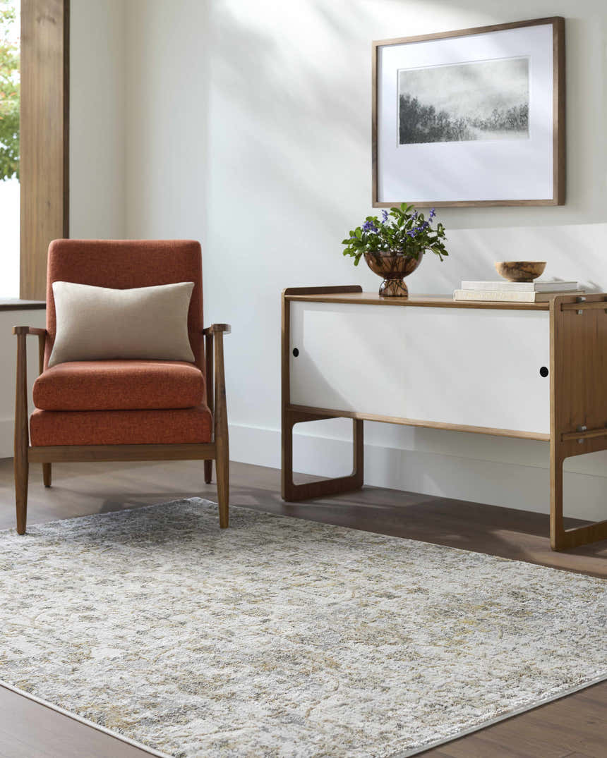 Living room scene with a Tiago Area Rug in beige, charcoal, and gray, styled with a mid-century modern chair and cabinet. Roomscene-Rectangle