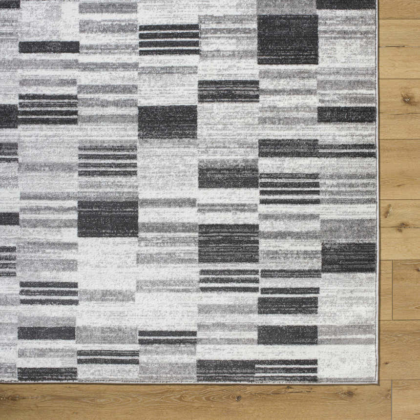 Close-up of the Tehya Gray Area Rug. Contemporary design with charcoal, silver gray, and slate blue blocks. Corner