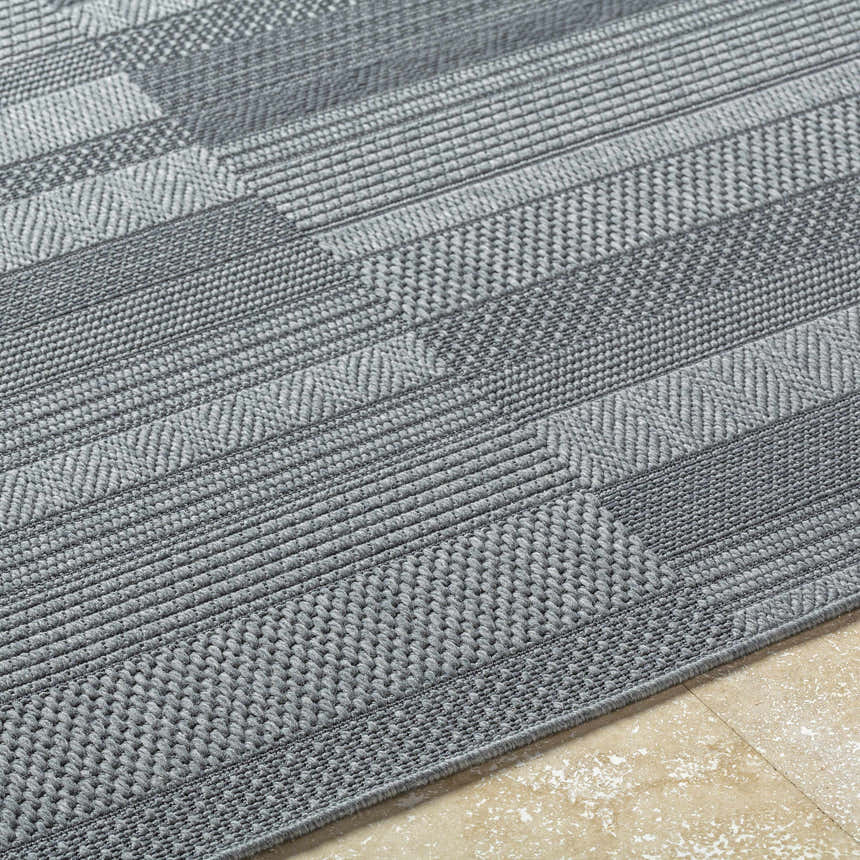 Close-up of the Thana Gray Area Rug showing its woven texture and geometric pattern in charcoal and gray tones. Texture