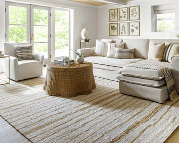 Living room with a beige Kamey Handmade Becki Owens x LIVABLISS rug, white sofa, and woven coffee table. Roomscene-Rectangle
