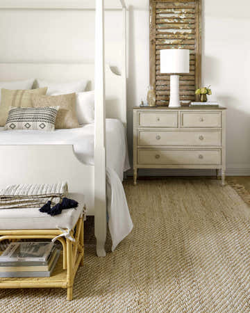 Farmhouse bedroom with a Varda Jute Area Rug, white four-poster bed, and neutral tones. Roomscene-Rectangle