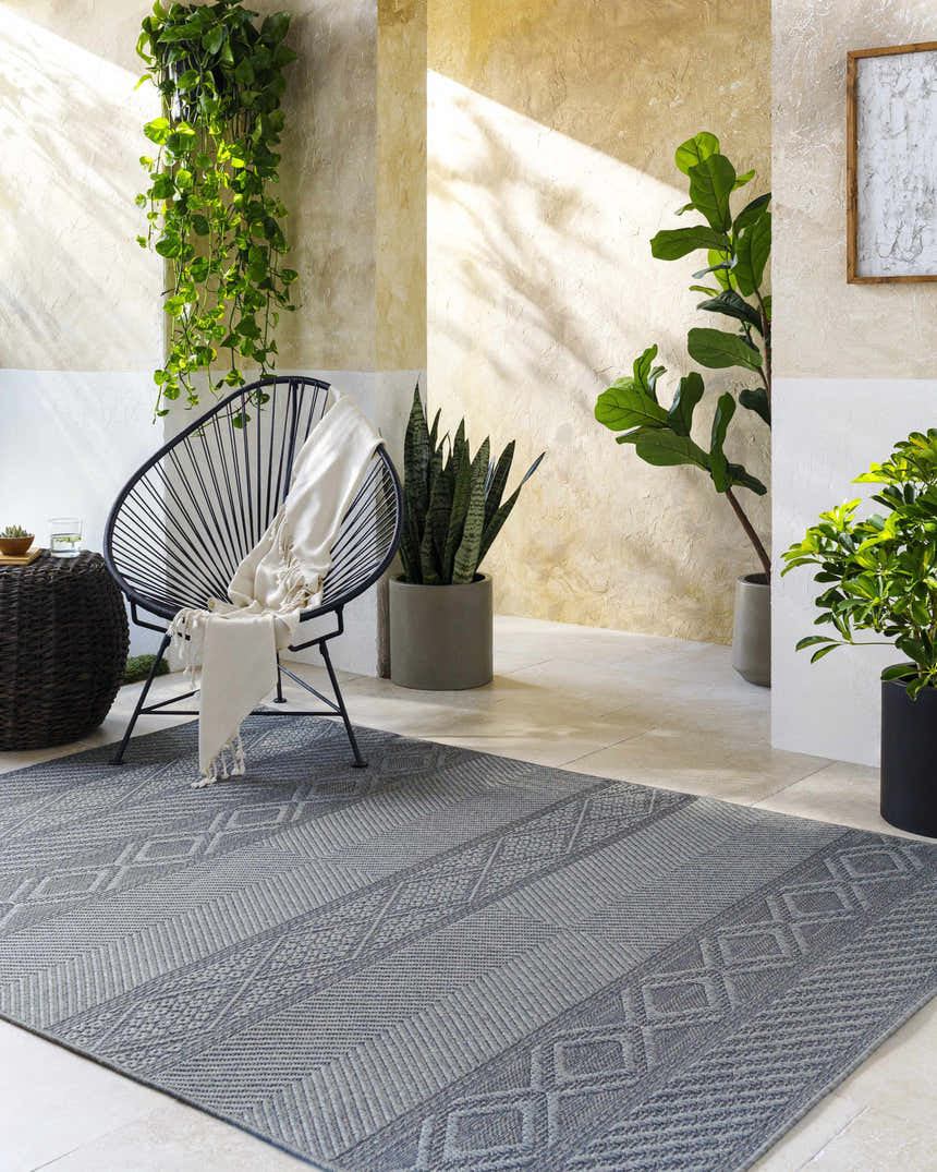 Serene patio scene with gray Aletha Area Rug, modern chair, and lush greenery. Farmhouse style. Roomscene-Rectangle