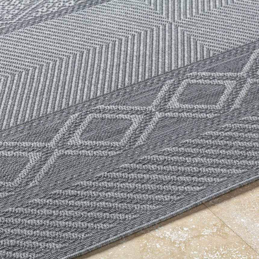 Close-up of the gray Aletha Area Rug showing a geometric diamond and chevron pattern with a machine woven texture. Texture